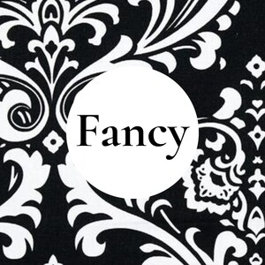 K&ouml;nnte beinhalten: Ein schwarz-wei&szlig;er Stoff mit Damastmuster, der einen zentralen wei&szlig;en Kreis mit dem Wort Fancy in schwarzer Serifenschrift aufweist. Das komplexe Blumen- und Rankenmuster bedeckt den Hintergrund in einem kontrastreichen, monochromen Farbschema.