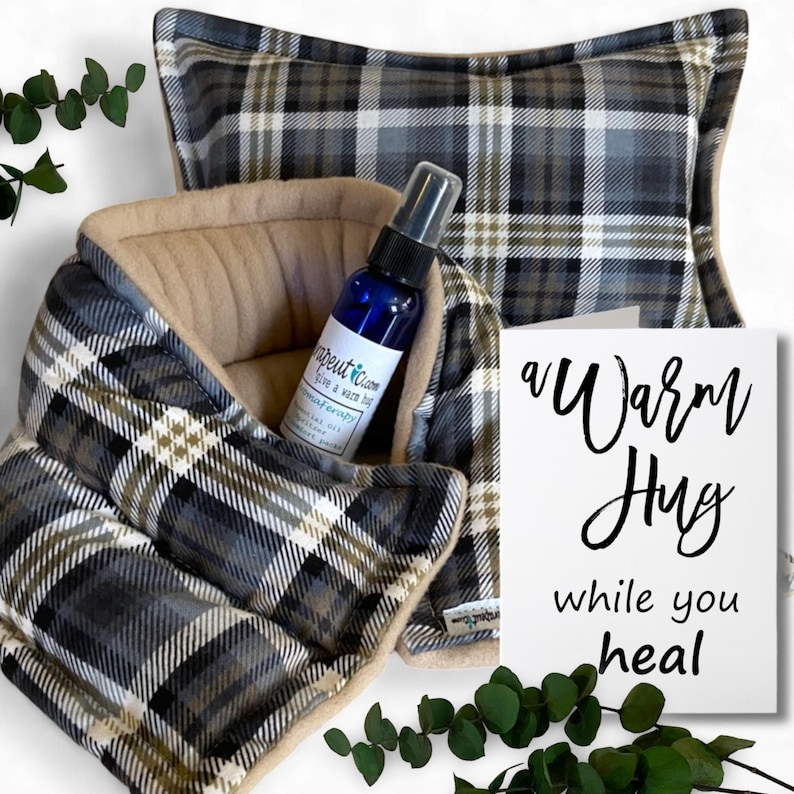 Get Well Gift Set of a plaid fabric heating pad with a matching pillow and a small bottle of essential oil. The heating pad is folded in half and the pillow is sitting on top of it. The bottle of essential oil is sitting on top of the pillow. There is a card that says 'a warm hug while you heal'.