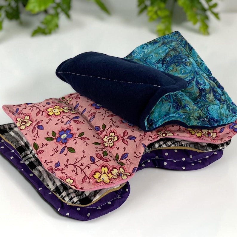 A stack of large eye pillows for soothing the face, used cold for menopause or warm for sinuses.