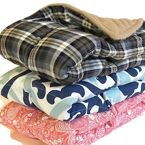 May include: Three folded fabric squares in different patterns. The top square is a plaid pattern in shades of blue, green, and white. The middle square is a blue and white swirl pattern. The bottom square is a pink and white paisley pattern.