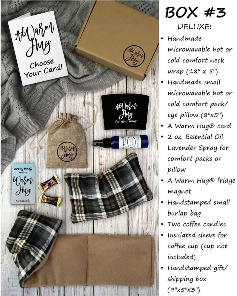 May include: A gift box labeled "Box #3 Deluxe!" contains a variety of items, including a brown neck wrap, a plaid eye pillow, a mug cozy, a small burlap bag, two coffee candies, a sleeve for a coffee cup, a card, a bottle of essential oil, and a fridge magnet. The box is hand-stamped with the words "Warm Hug".