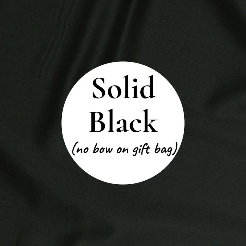 K&ouml;nnte beinhalten: Ein einfarbiger schwarzer Stoffhintergrund mit einer wei&szlig;en kreisf&ouml;rmigen Grafik in der Mitte. Der Text im Kreis lautet Solid Black und darunter in kleinerer Schrift (no bow on gift bag). Der Stoff weist sichtbare Falten und eine matte Textur auf.