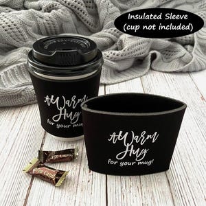 May include: Black insulated coffee sleeve with white text that reads "A Warm Hug for your mug!"