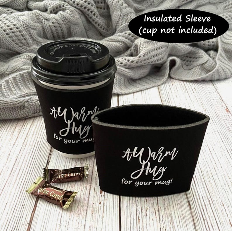 May include: Black insulated coffee sleeve with white text that reads "A Warm Hug for your mug!"