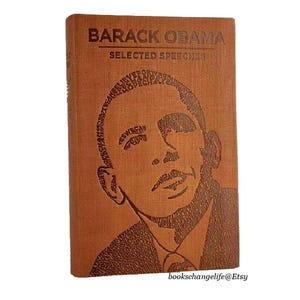 May include: A brown leather-bound book with the title "Barack Obama Selected Speeches" embossed on the cover. The cover features a portrait of Barack Obama created using the words from his speeches.