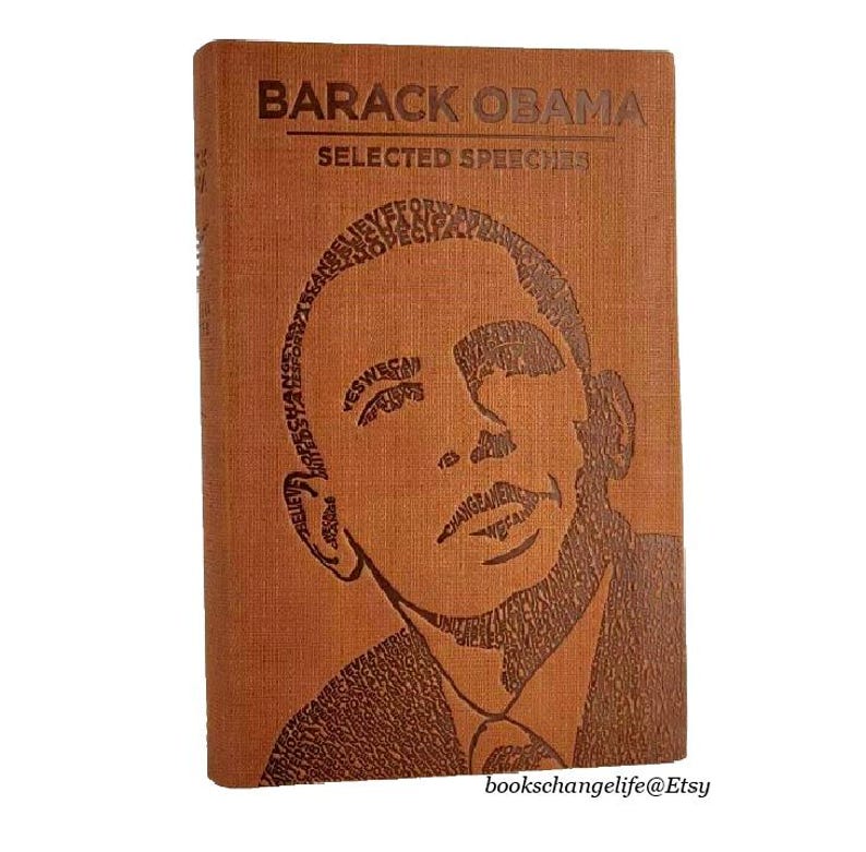 May include: A brown leather-bound book with the title "Barack Obama Selected Speeches" embossed on the cover. The cover features a portrait of Barack Obama created using the words from his speeches.