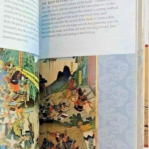 K&ouml;nnte beinhalten: Eine Seite aus einem Buch mit dem Titel "The Water Book" mit einer detaillierten Illustration einer Samurai-Schlacht. Der Text auf der Seite behandelt die Technik "Der K&ouml;rper an der Stelle des Langschwertes" im Schwertkampf.