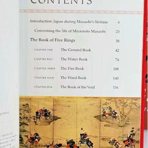 K&ouml;nnte beinhalten: Ein Buch mit dem Titel "Das Buch der F&uuml;nf Ringe" von Miyamoto Musashi. Der Inhalt des Buches ist aufgelistet, einschlie&szlig;lich der Kapitel "Das Buch der Erde", "Das Buch des Wassers", "Das Buch des Feuers", "Das Buch des Windes" und "Das Buch der Leere".