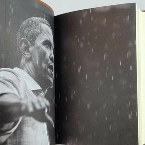 May include: A black and white photo of a man speaking in front of a crowd. The photo is grainy and has a rain-like effect.