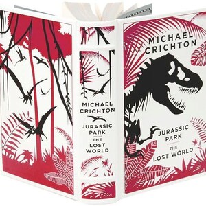 May include: A white book cover with red and black illustrations of a jungle scene and a dinosaur. The title is "Jurassic Park The Lost World" by Michael Crichton.