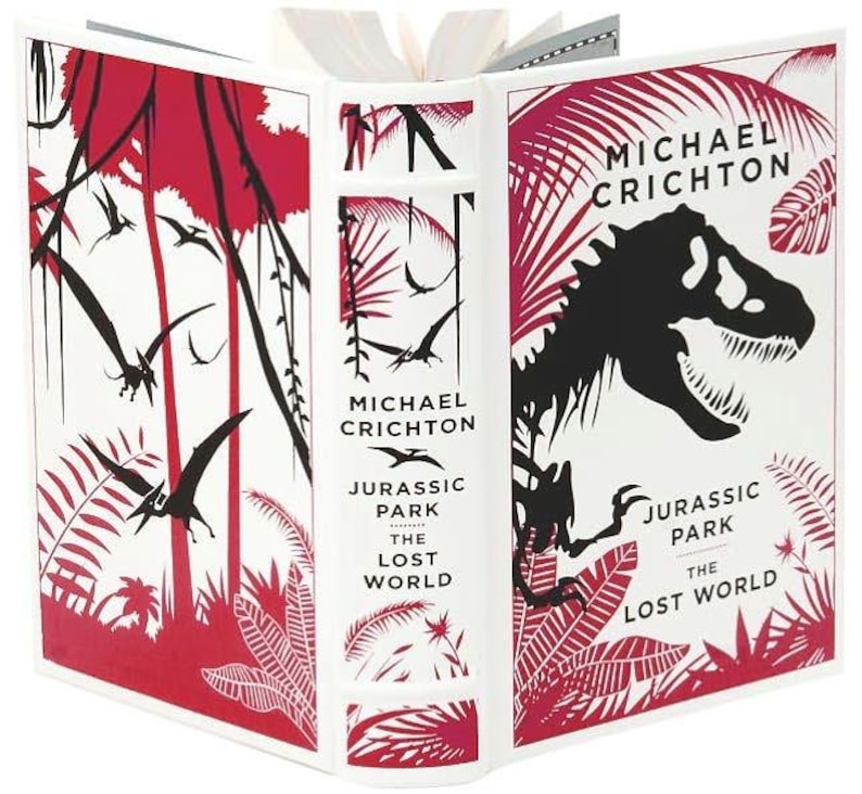 May include: A white book cover with red and black illustrations of a jungle scene and a dinosaur. The title is "Jurassic Park The Lost World" by Michael Crichton.