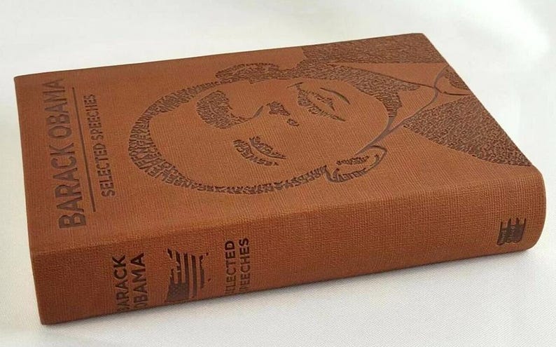 May include: A brown leather-bound book with the title "Barack Obama Selected Speeches" embossed on the cover. The cover features a portrait of Barack Obama created from the words of his speeches.