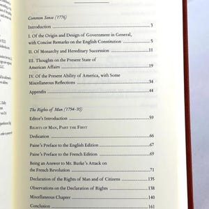 May include: An open book displaying the contents page. Titles include "Common Sense (1776)" and "The Rights of Man (1794-95)". The book's spine is red.