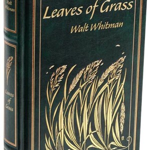 May include: A green leather-bound book with gold lettering titled "Leaves of Grass" by Walt Whitman. The cover features a gold illustration of blades of grass.