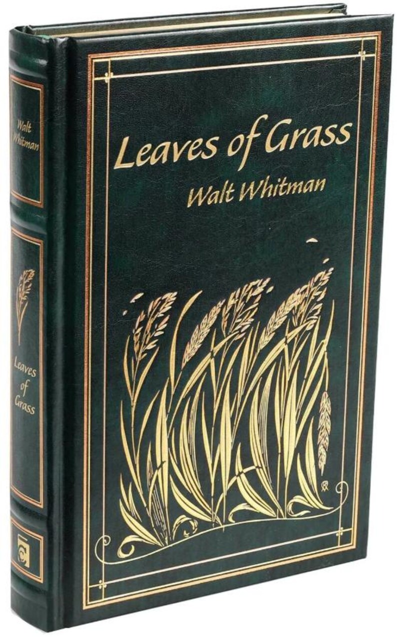 May include: A green leather-bound book with gold lettering titled "Leaves of Grass" by Walt Whitman. The cover features a gold illustration of blades of grass.