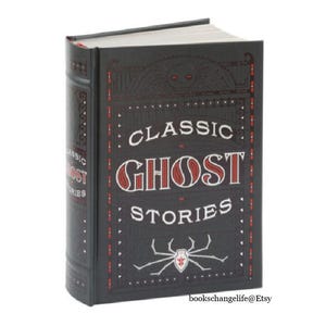 May include: A black hardcover book with the title "Classic Ghost Stories" in red and white lettering. A red spider with a white body is on the front cover.