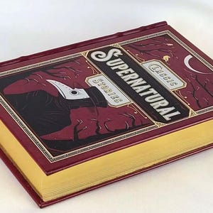 May include: A burgundy hardback book with gold accents and a title that reads "Classic Supernatural Stories". The cover features a dark illustration of a figure wearing a plague doctor mask.
