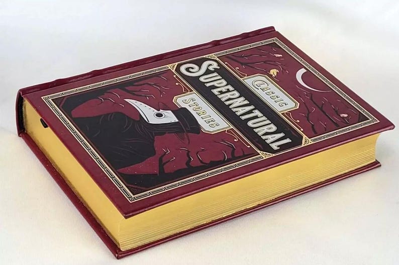 May include: A burgundy hardback book with gold accents and a title that reads "Classic Supernatural Stories". The cover features a dark illustration of a figure wearing a plague doctor mask.
