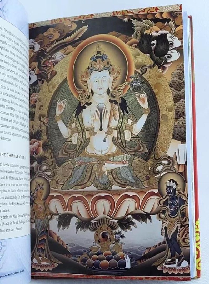 K&ouml;nnte beinhalten: Offenes Buch mit einer detaillierten Illustration einer sitzenden Figur mit mehreren Armen, umgeben von verzierten Gold- und Braunt&ouml;nen. Die Figur hat helle Haut und tr&auml;gt eine Krone. Der Text auf der linken Seite lautet "THE THIRTEENTH DAY".