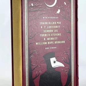 May include: A burgundy hardback book with a gold spine. The cover features a black and white illustration of a person wearing a plague doctor mask in a dark forest setting. The text on the cover reads "WITH STORIES BY EDGAR ALLAN POE H.P. LOVECRAFT VERNON LEE FRANCIS STEVENS A. MERRITT WILLIAM HOPE HODGSON AND OTHERS".
