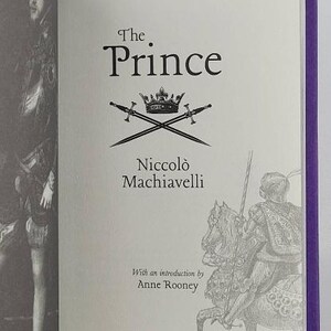 May include: A book titled "The Prince" by Niccol&ograve; Machiavelli with an introduction by Anne Rooney. The cover features a black and white illustration of a knight on horseback and a crown with two swords crossed underneath.