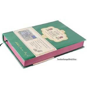 May include: A green hardcover book with a pink spine. The book is titled "A Study in Scarlet" by Sir Arthur Conan Doyle. The book is closed and the cover is visible. The book is a classic novel.