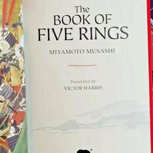 K&ouml;nnte beinhalten: Das Buch der F&uuml;nf Ringe von Miyamoto Musashi, &uuml;bersetzt von Victor Harris. Der Buchumschlag zeigt eine Schwarzwei&szlig;illustration eines B&auml;ren mit einem Stern dar&uuml;ber und dem Wort "Arcturus" darunter.