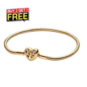 May include: A gold-toned snake chain bracelet featuring a heart-shaped clasp. The clasp displays an intricate tree of life motif with small embedded clear stones. The image includes a graphic label with the text BUY 2 GET 1 FREE.