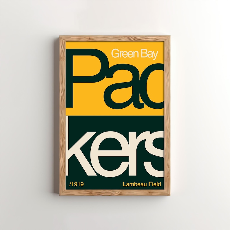 May include: A framed print with a yellow background and green text that reads "Green Bay Packers" with the year "1919" and "Lambeau Field" below the text.