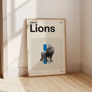 Op de afbeelding: Een ingelijste poster met een witte achtergrond en de tekst "Detroit Lions" in zwart. De poster toont een zwart-witte afbeelding van een leeuw die voor een blauwe en grijze streep staat.