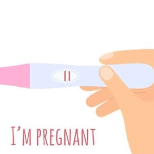 Puede incluir: Una prueba de embarazo blanca y rosa con dos líneas, lo que indica un resultado positivo. La prueba se sostiene en una mano con el texto "I'M PREGNANT" debajo.