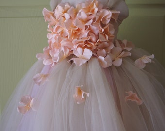 Puede incluir: Un vestido de tul con un corpiño de flores de color melocotón. El vestido está hecho de capas de tul y tiene un diseño de flores de color melocotón en el corpiño. El vestido es perfecto para una ocasión especial.
