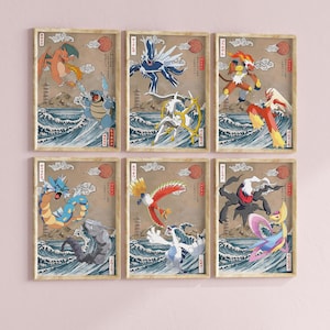 May include: Six framed prints featuring Pokemon characters in a Japanese art style. The prints are on a light pink wall. Each print features a different Pokemon character, including a red and orange dragon, a blue and white bird, a red and yellow fire creature, a blue and green water creature, a red and yellow bird, and a black and white ghost creature.
