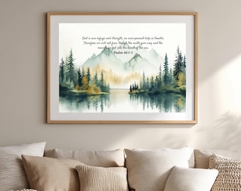 May include: A framed horizontal wall art print featuring a watercolor landscape of mountains, a lake, and pine trees. The text reads: God is our refuge and strength, an ever-present help in trouble. Therefore we will not fear, though the earth give way and the mountains fall into the heart of the sea. Psalm 46:1-2.