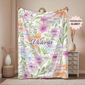 May include: A personalized blanket featuring a floral design with the name "Victoria" in a script font. The blanket is white with colorful flowers and inspirational quotes from the Bible. The words "PERSONALIZED BLANKET" are also visible.