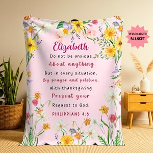 May include: A personalised pink blanket with floral accents and the name "Elizabeth" in script. The blanket features the text "Do not be anxious About anything..." and "PHILIPPIANS 4:6". A "PERSONALIZED BLANKET" sticker is in the upper right corner.