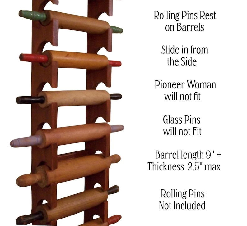 Op de afbeelding: Een bruin houten deegrollerrek met verschillende deegrollers. Het rek bevat deegrollers met verschillende handvatkleuren. De tekst luidt "Rolling Pins Rest on Barrels" en "Lengte cilinder 23 cm + Dikte 6,35 cm max".