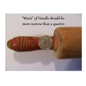 May include: A wooden rolling pin with a red painted handle featuring visible wear and chipped paint. A silver US quarter coin is placed on the handle for scale. The text above reads: "Waist" of Handle should be more narrow than a quarter.