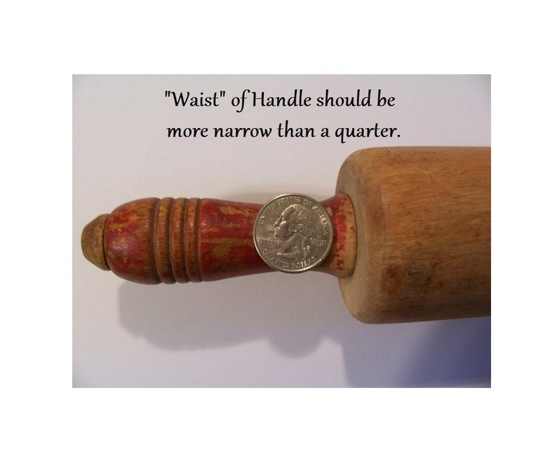 May include: A wooden rolling pin with a red painted handle featuring visible wear and chipped paint. A silver US quarter coin is placed on the handle for scale. The text above reads: "Waist" of Handle should be more narrow than a quarter.