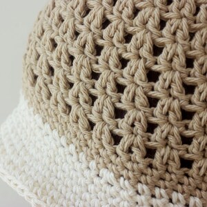 May include: A crocheted hat with a beige crown and a white brim.