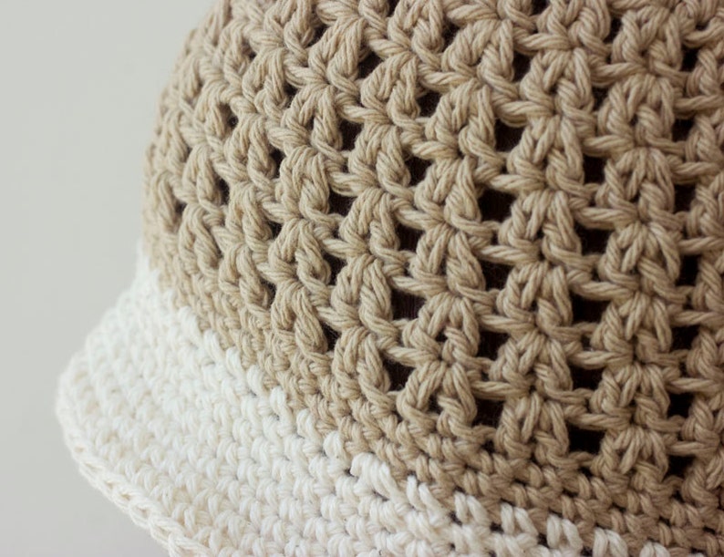 May include: A crocheted hat with a beige crown and a white brim.