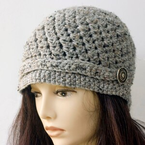 May include: Gray crocheted beanie with a button detail. The beanie has a slouchy fit and a wide brim.