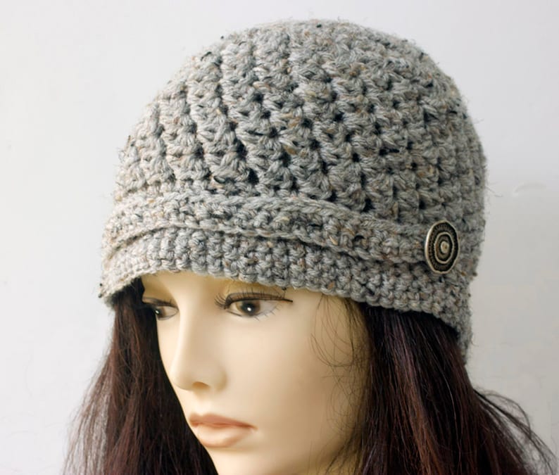 May include: Gray crocheted beanie with a button detail. The beanie has a slouchy fit and a wide brim.