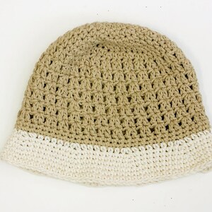 May include: A crocheted hat with a beige crown and a white brim.