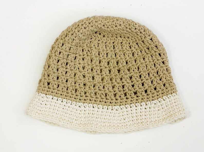 May include: A crocheted hat with a beige crown and a white brim.