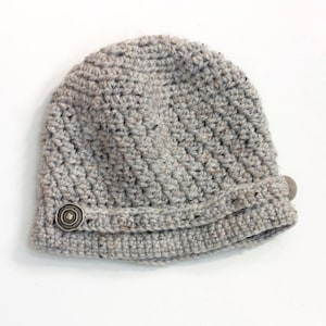 May include: A gray crocheted beanie with a decorative button on the side.