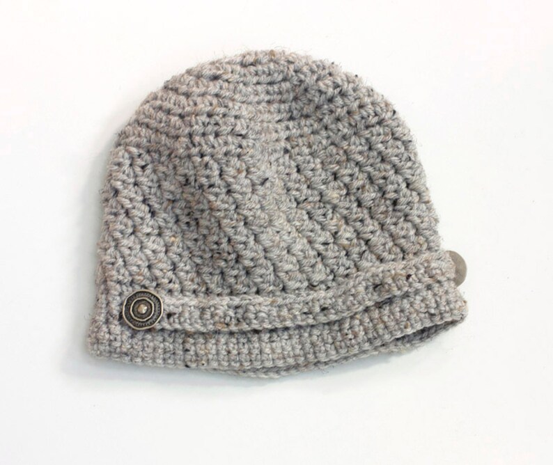 May include: A gray crocheted beanie with a decorative button on the side.