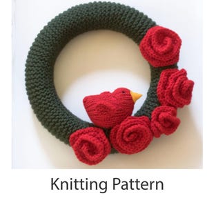 Könnte beinhalten: Strickanleitung für einen grünen Kranz mit roten Filzrosen und einem roten Filzvogel.