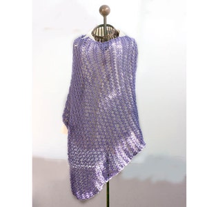 May include: A purple crochet poncho with a loose, open weave. The poncho is draped over a mannequin and has a slightly asymmetrical hemline.