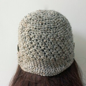 May include: A gray crocheted beanie hat with a textured pattern. The hat is made with a thick yarn and has a slouchy fit.